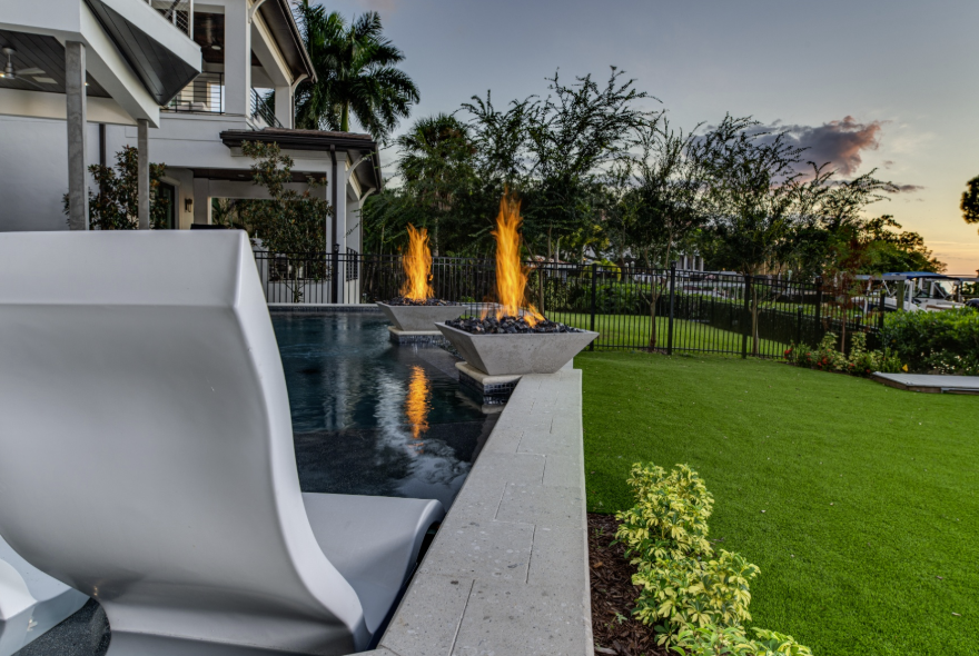 Custom Wahoo Pools build with fire bowls and in-water ledge lounger at sunset